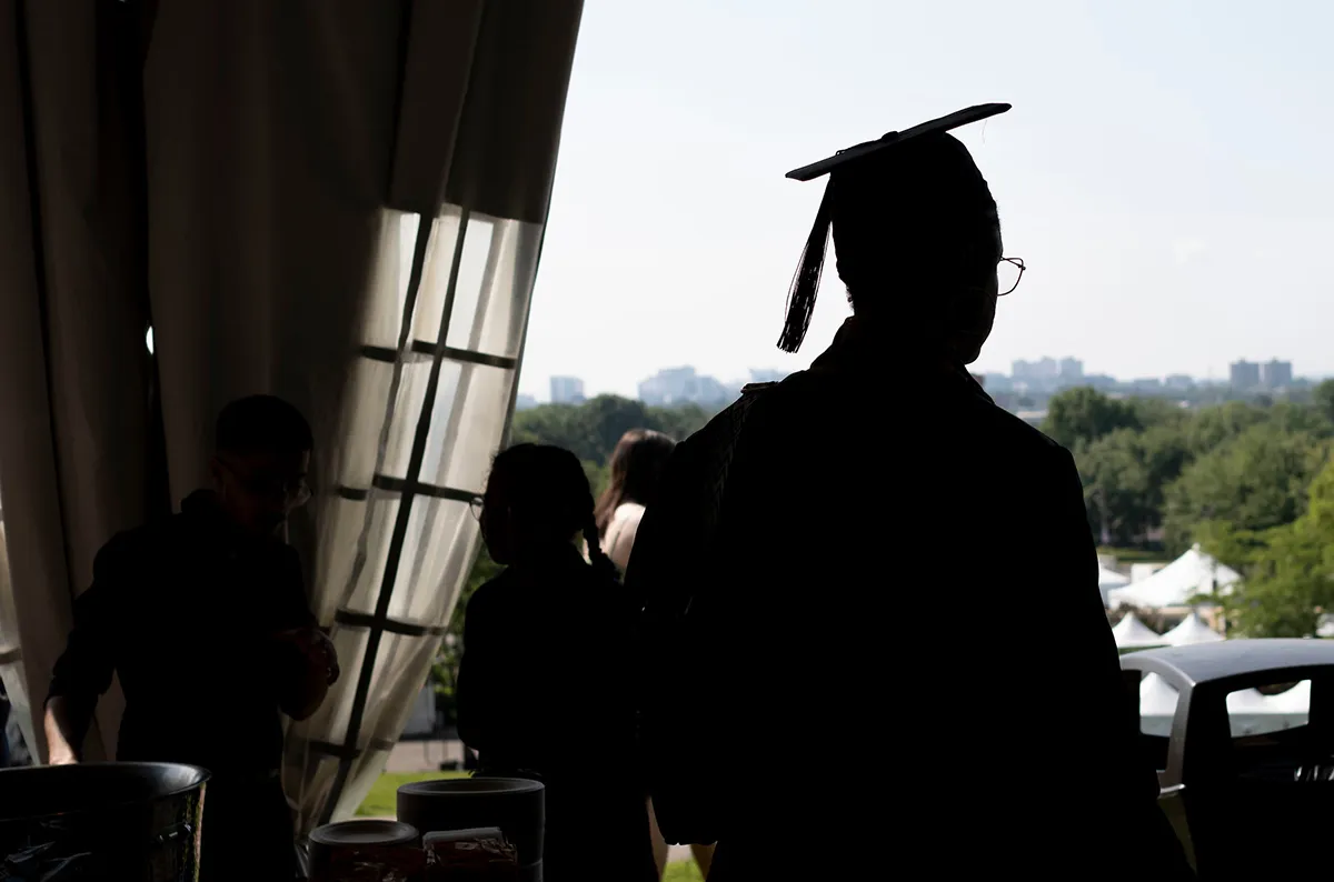 Silhouette of student wearing cap and gown