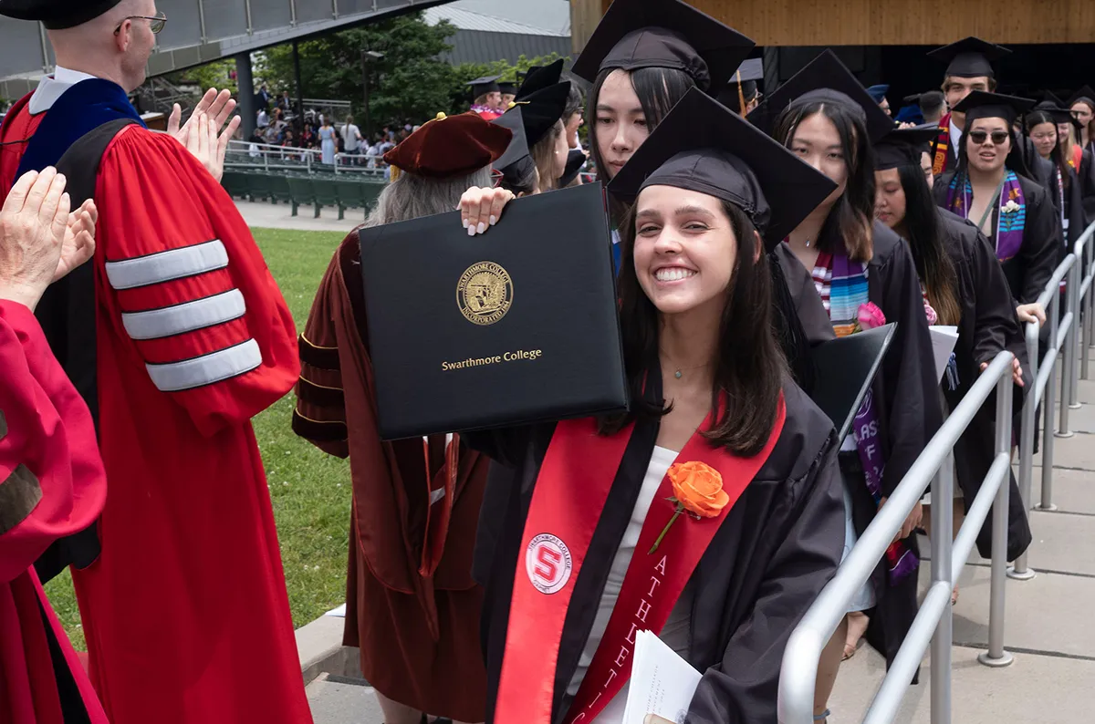 Student proudly holds up diploma folio after graduation