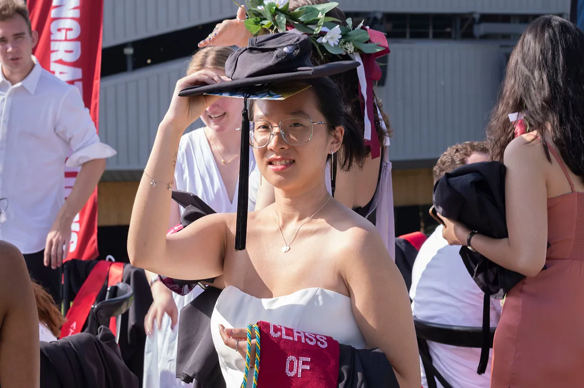 Student holds adorned graduation cap before commencement ceremony