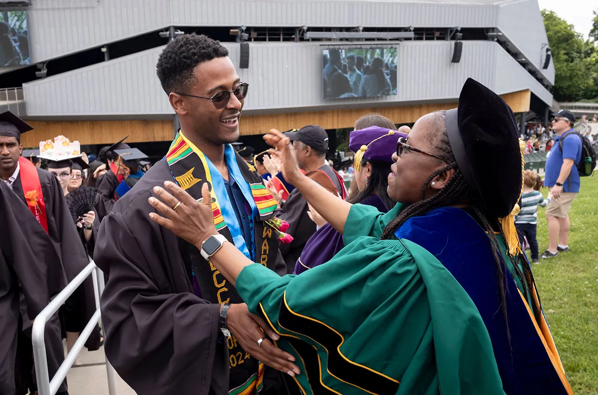 Student hugs faculty member after commencement