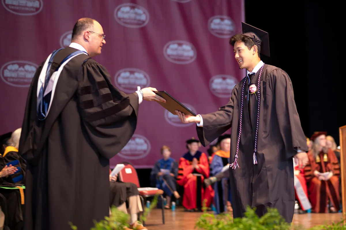 Student receives diploma from acting co-president Rob Goldberg