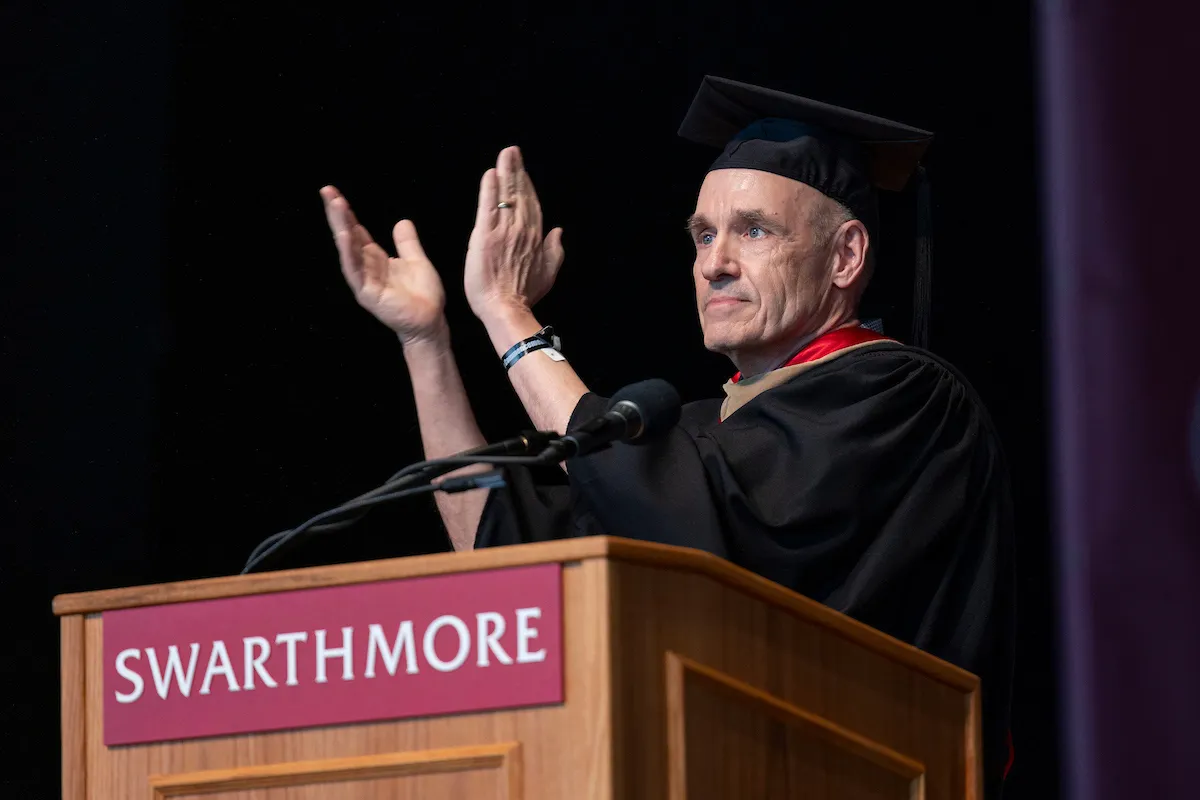 Koof Kalkstein claps hands while standing behind podium