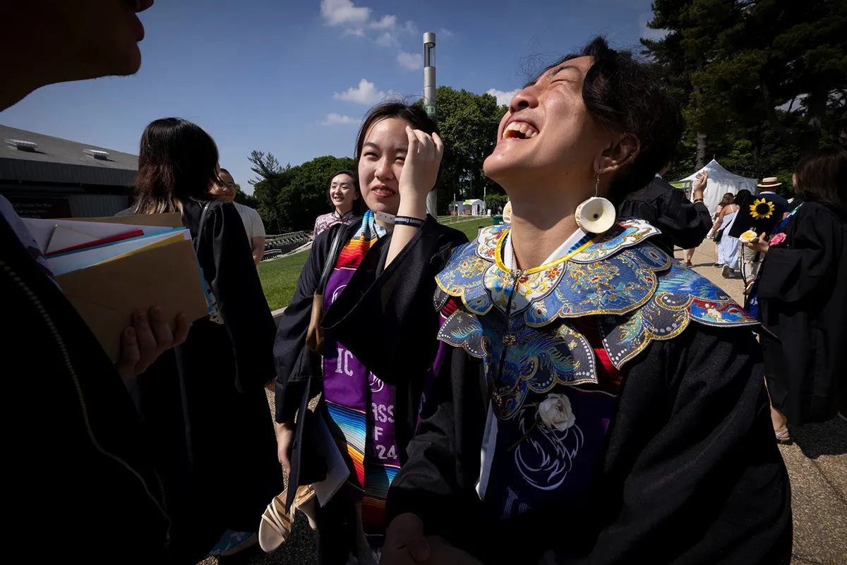 Students smile and laugh together after commencement ceremony