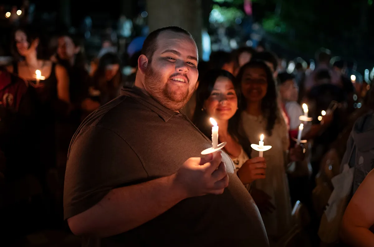 Students hold candles in outdoor amphitheater during Last Collection