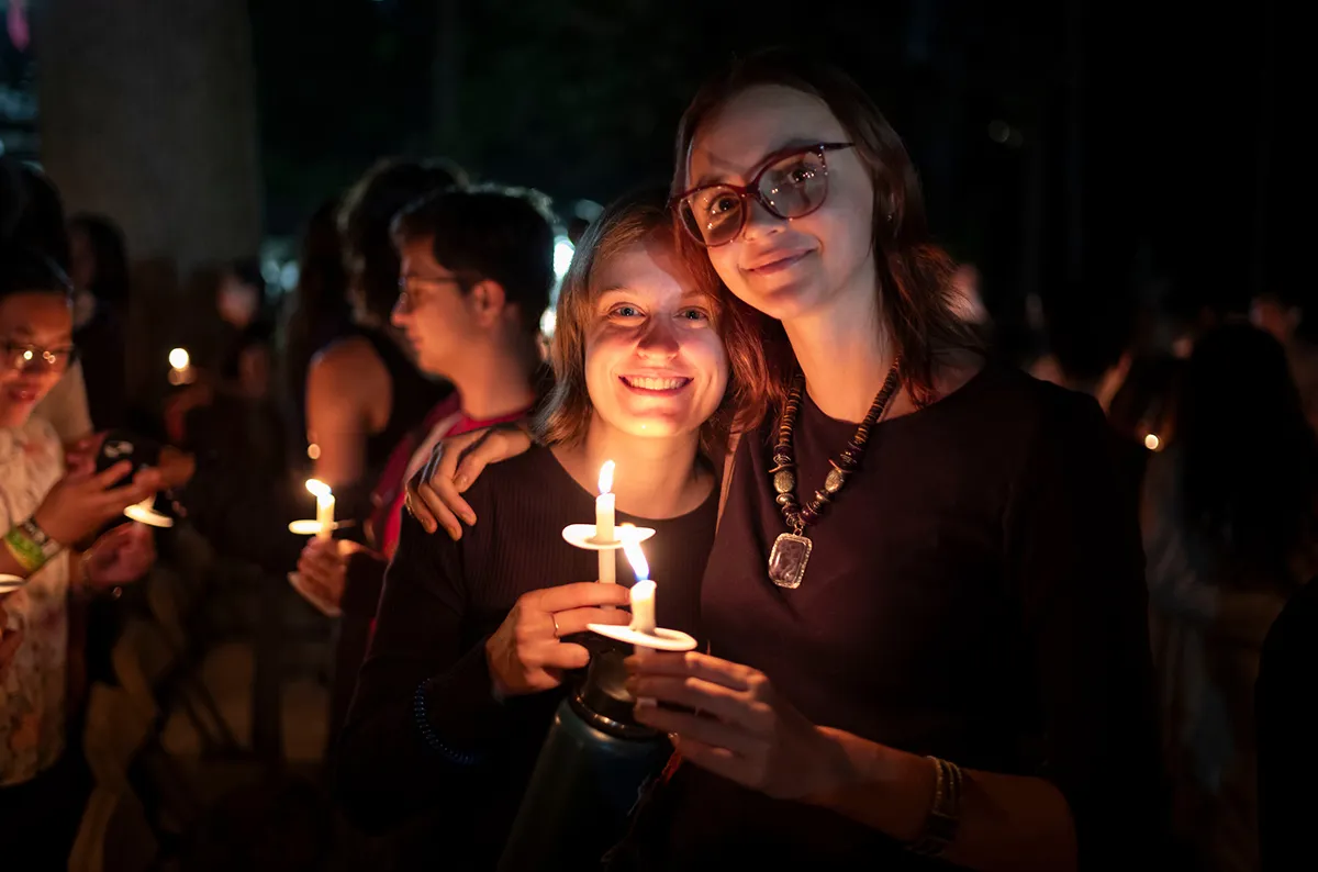 Students hold candles in outdoor amphitheater during Last Collection