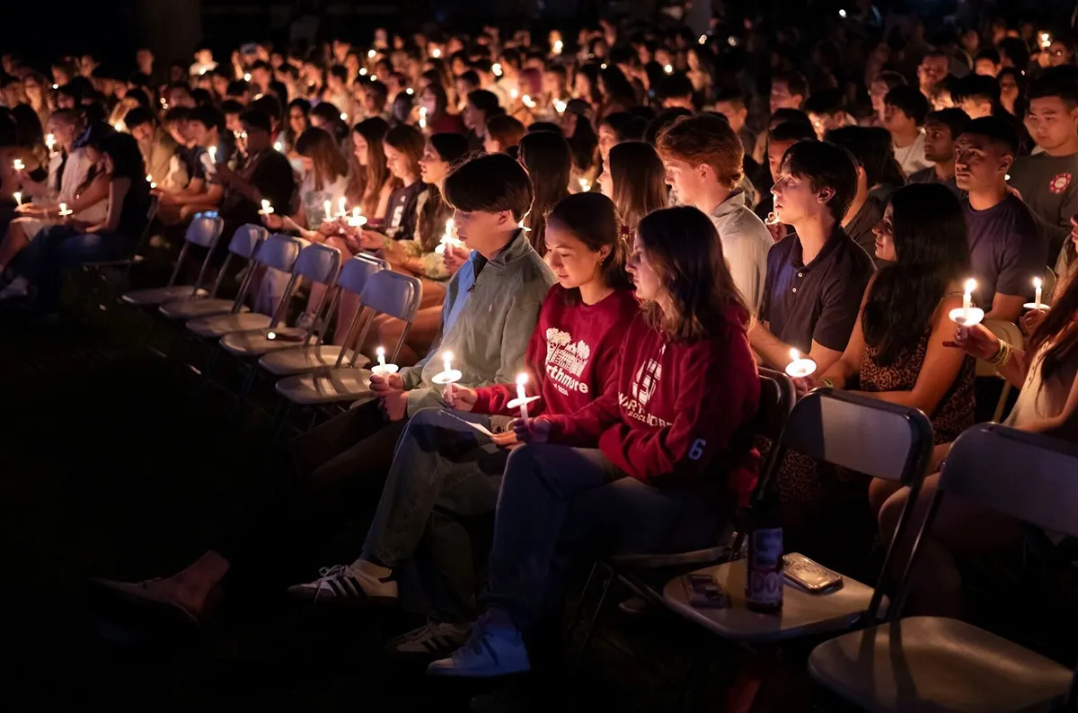 Students hold candles in outdoor amphitheater during Last Collection