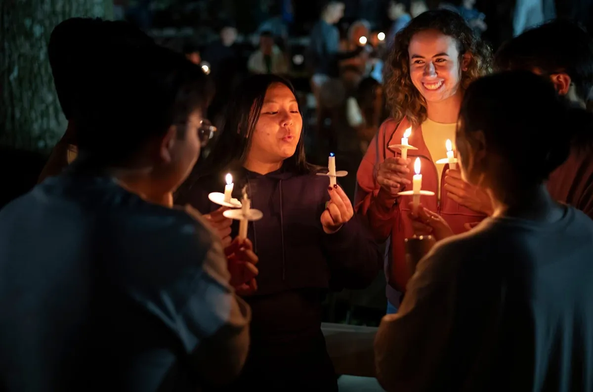 Students hold candles in outdoor amphitheater during Last Collection