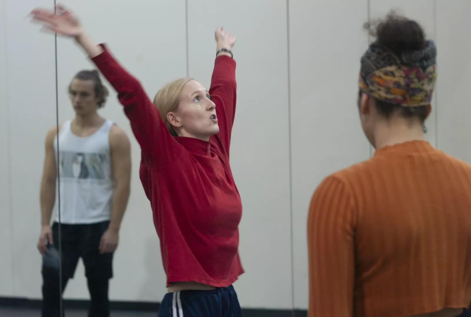 A dancer with arms upraised teaching other dancers