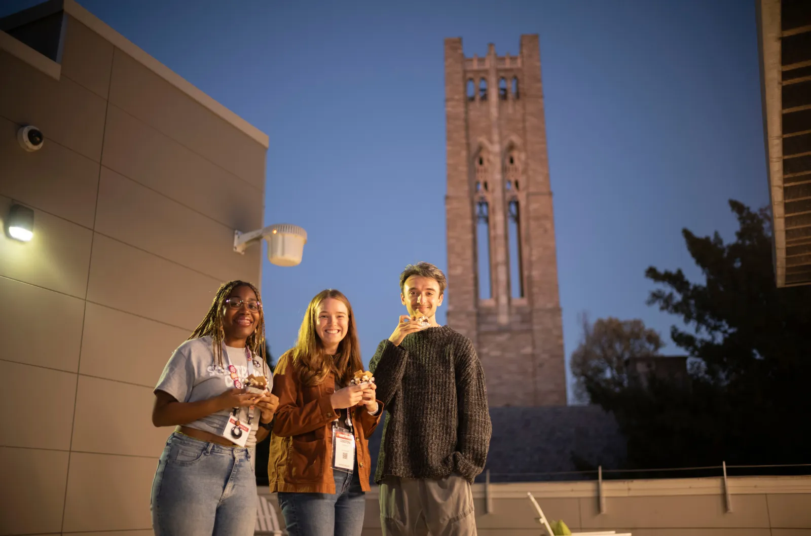 Three people eat outside with Clothier Belltower in distant background