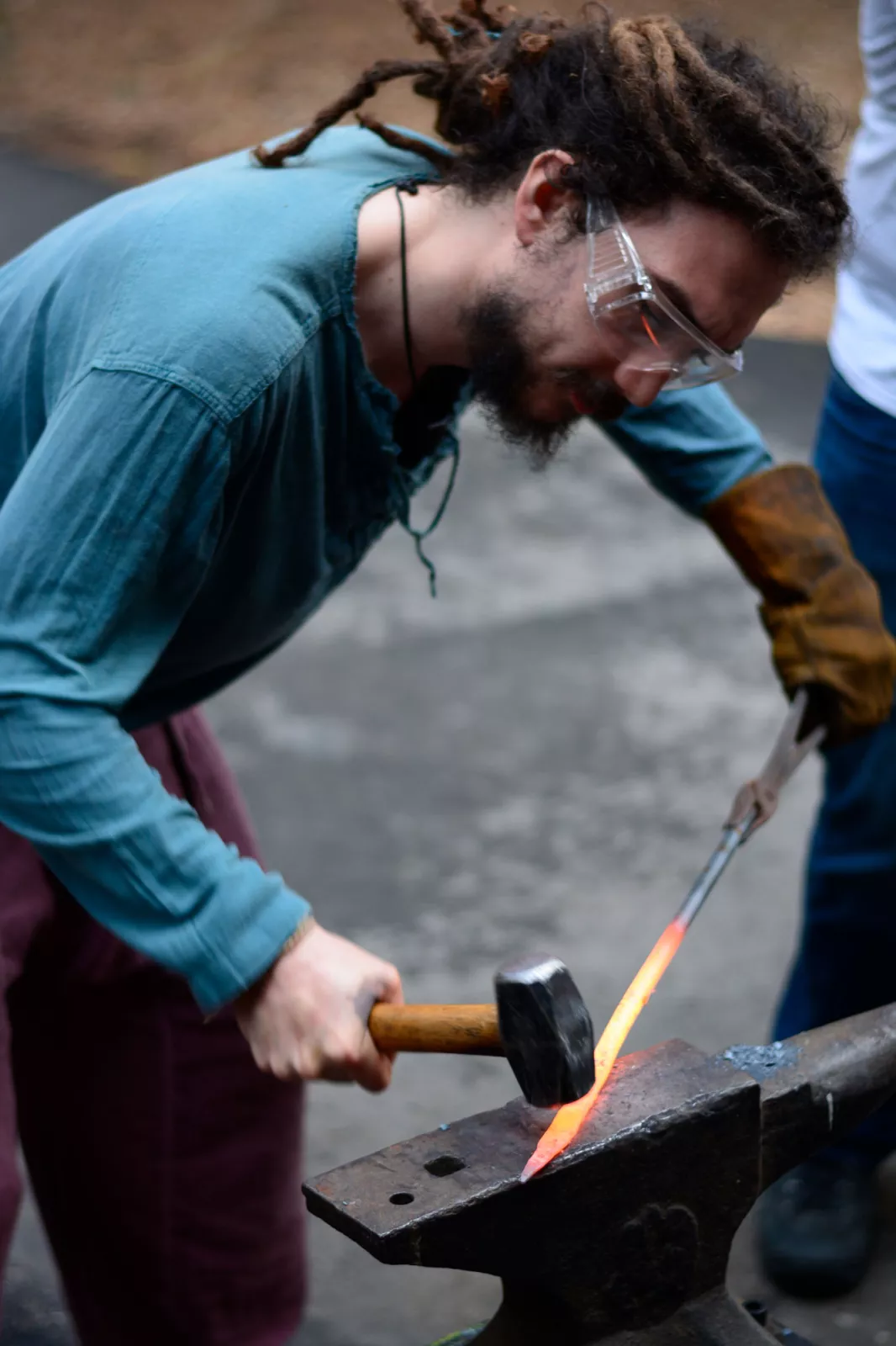 A student uses a hammer to flatten hot metals