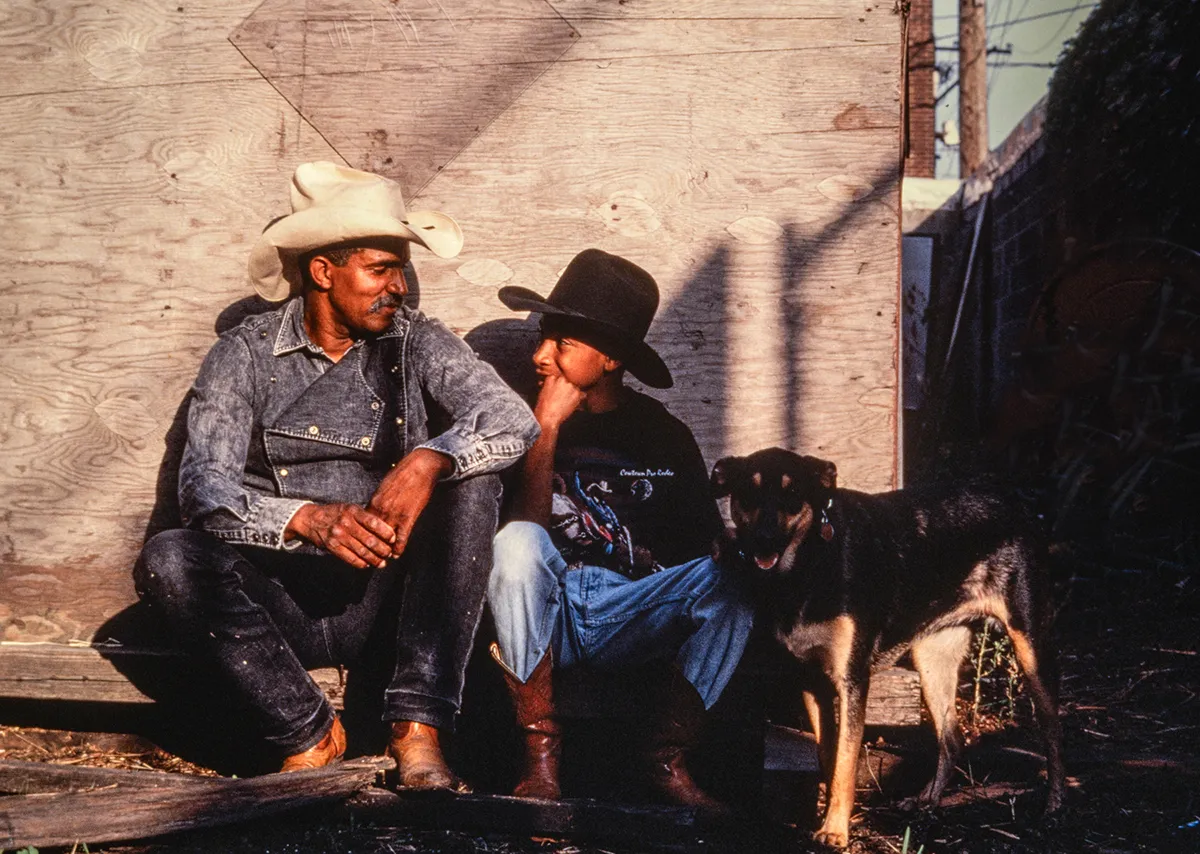 Older man in cowboy hat talks to a young man