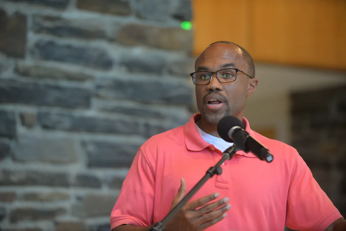 Person wearing pink shirt speaks at podium