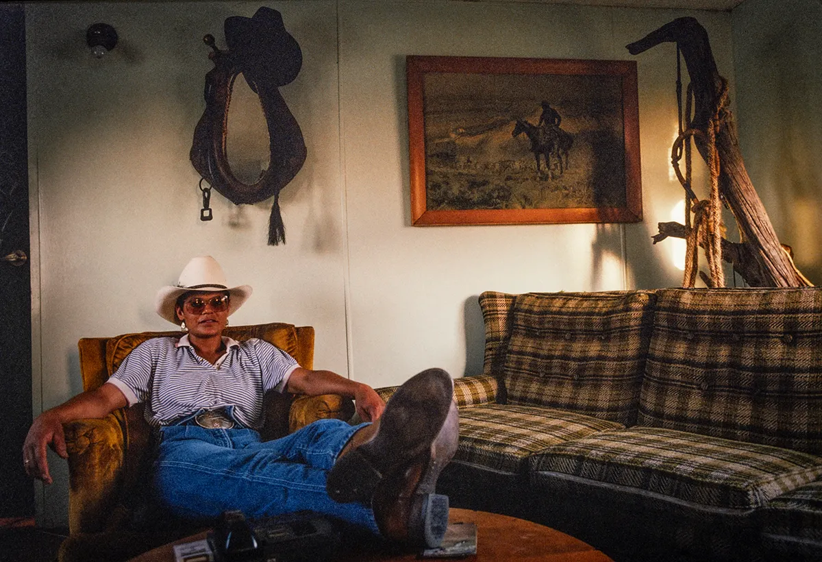 Woman wearing cowboy gear relaxes at home.