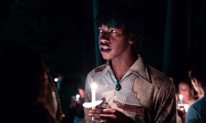 Student with candle looks off to side