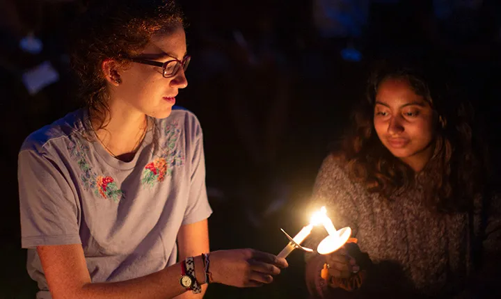 One student transfers flame to another student's candle