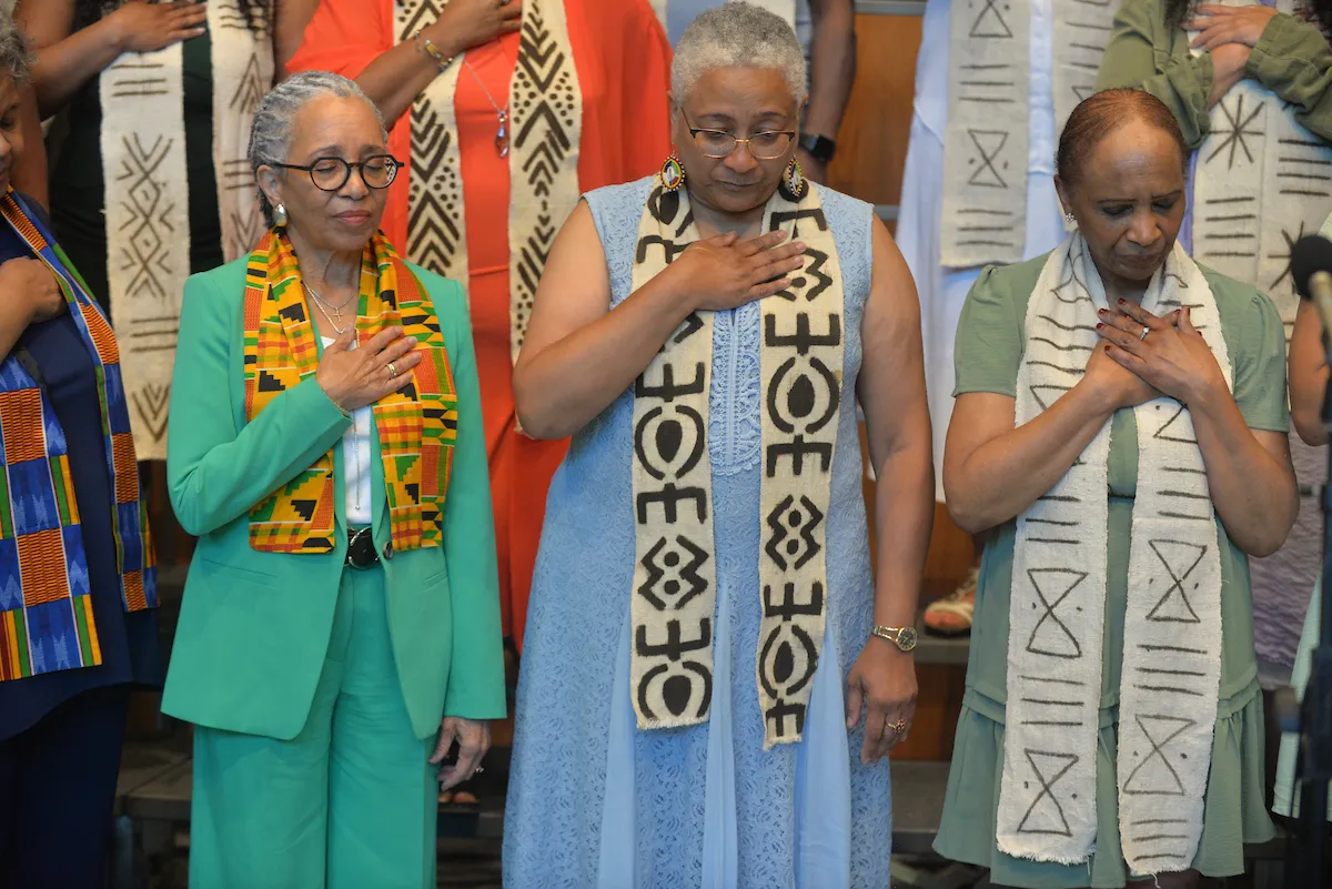 Gospel choir members stand with hand over heart