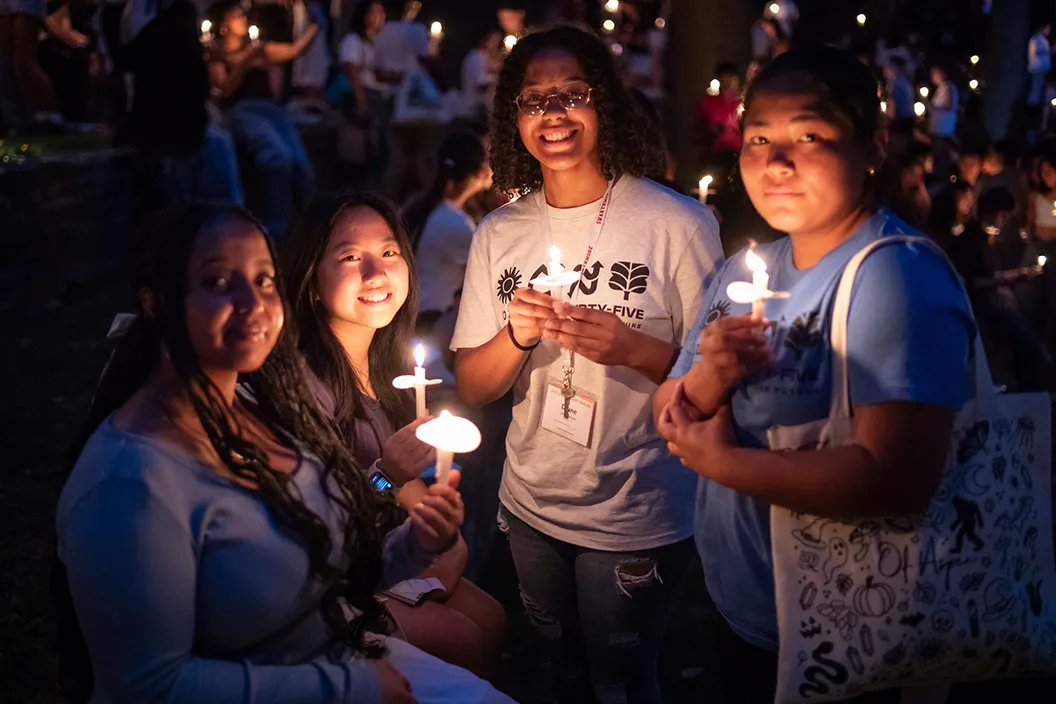 Students hold candles during First Collection