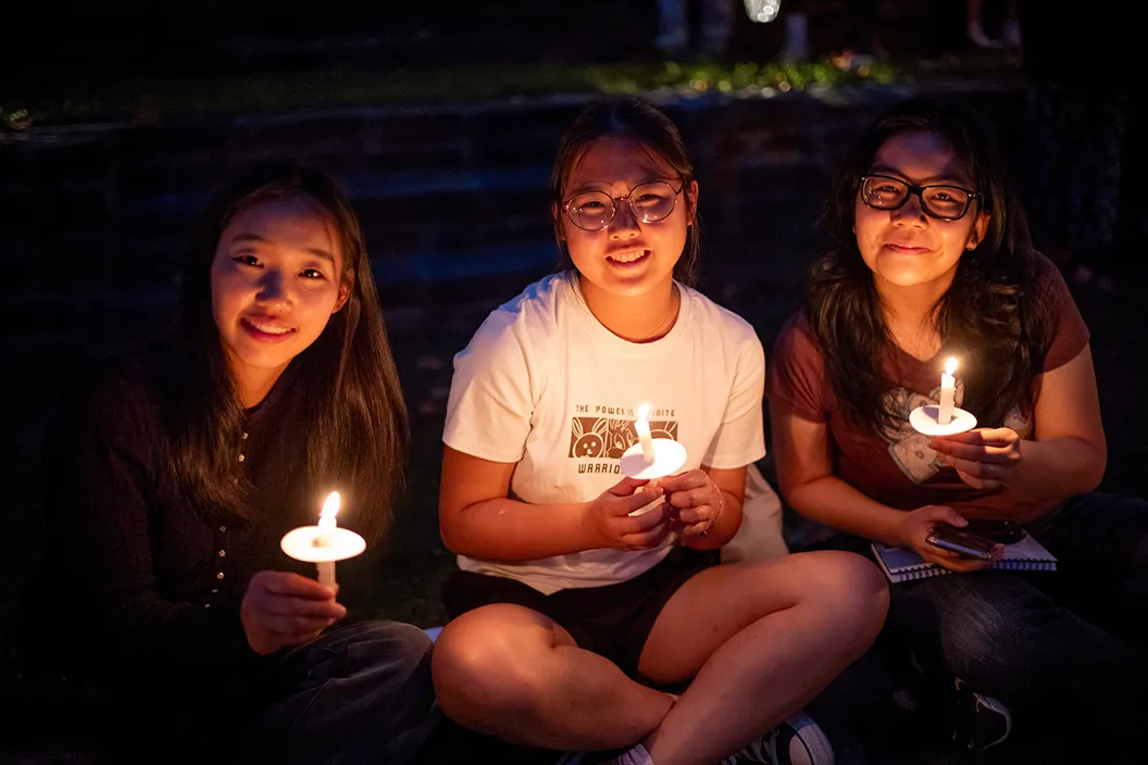 Seated students hold candles during Last Collection