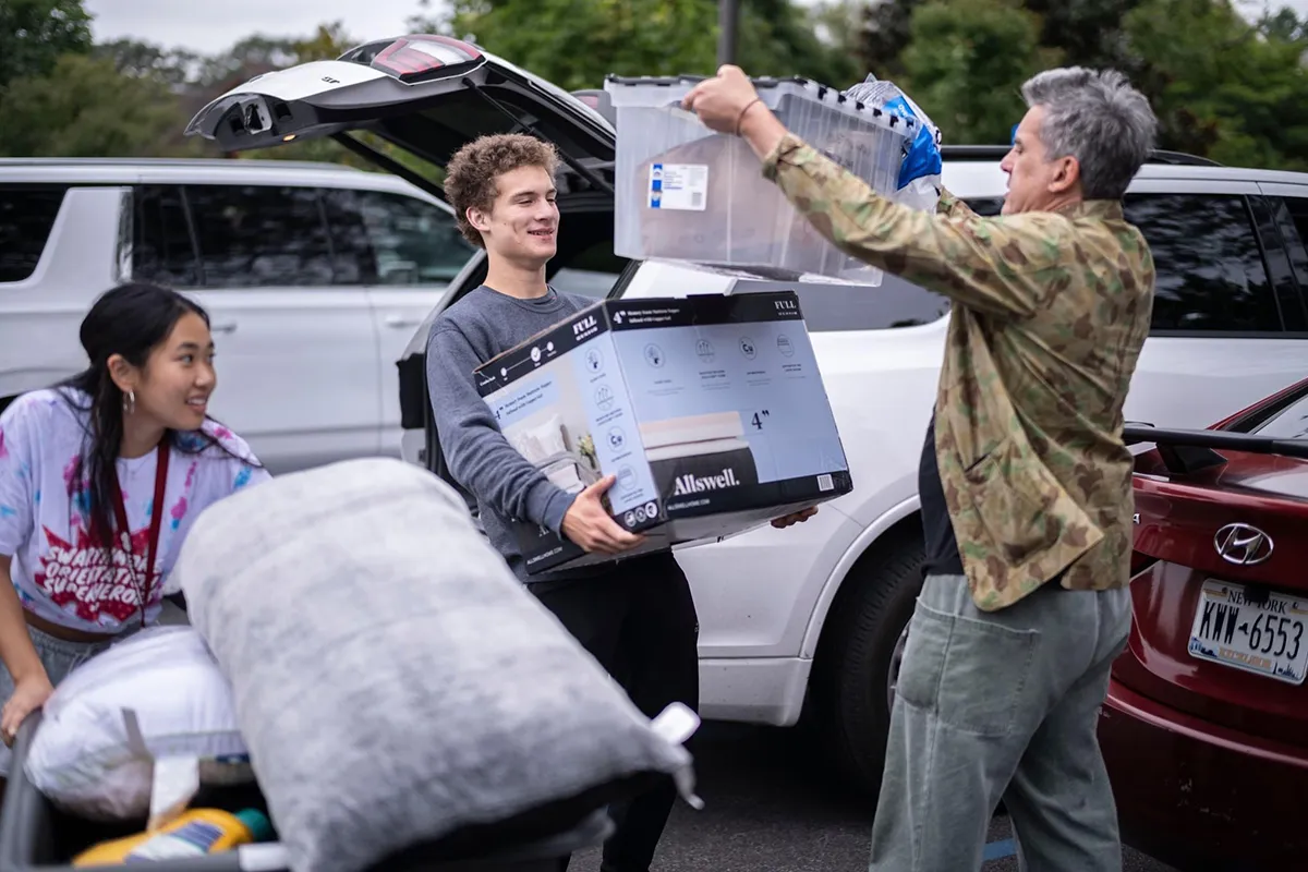 People carry bins with dorm room items