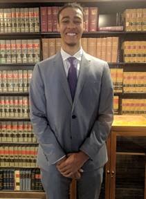 David Buckley on the first day day of work in the offices of the NAACP LDF, standing in front of various legal texts