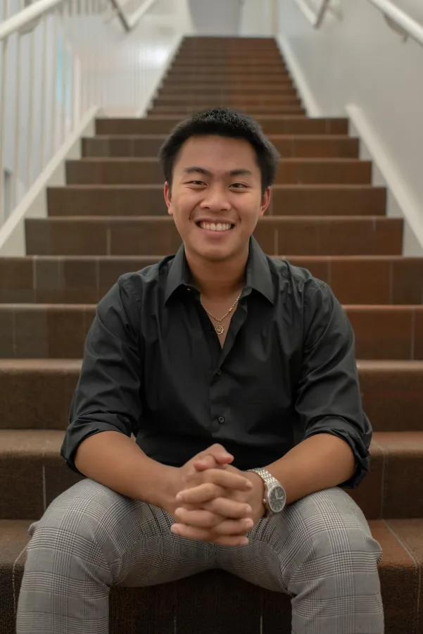 Aaron Thammavongxay '25 poses for a photo on a set of stairs