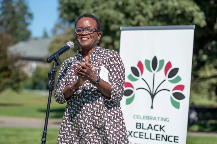 President Valerie Smith claps with Black Excellence sign in background