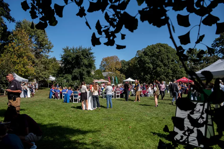 Community members eat and mingle on lawn near Trotter Hall