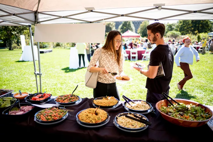 Students eat food under a tent