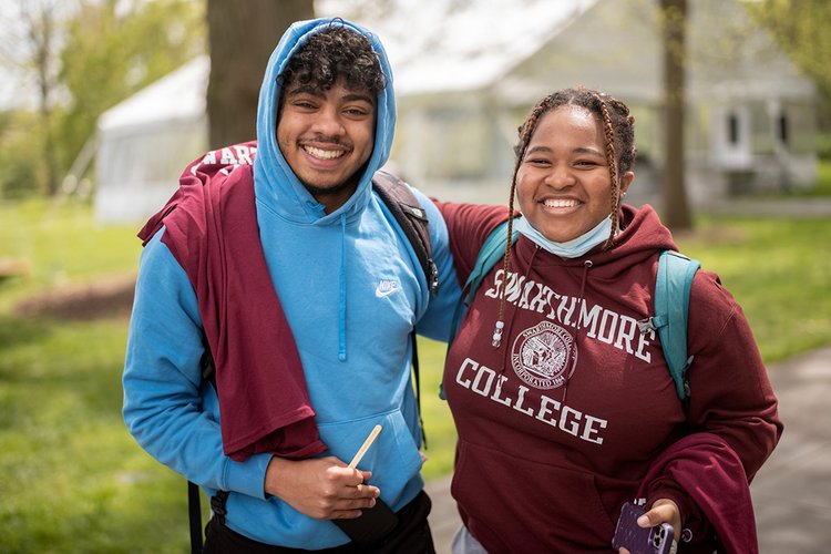 Two students wearing garnet pose together outdoors