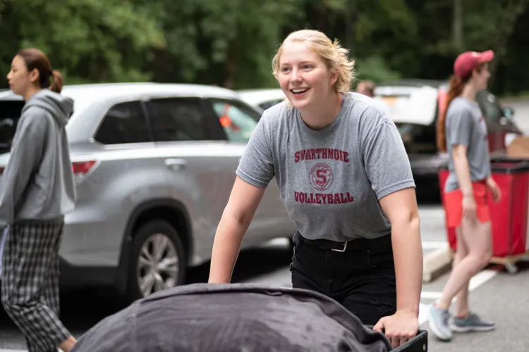 Student pushes cart with belongings into dorm