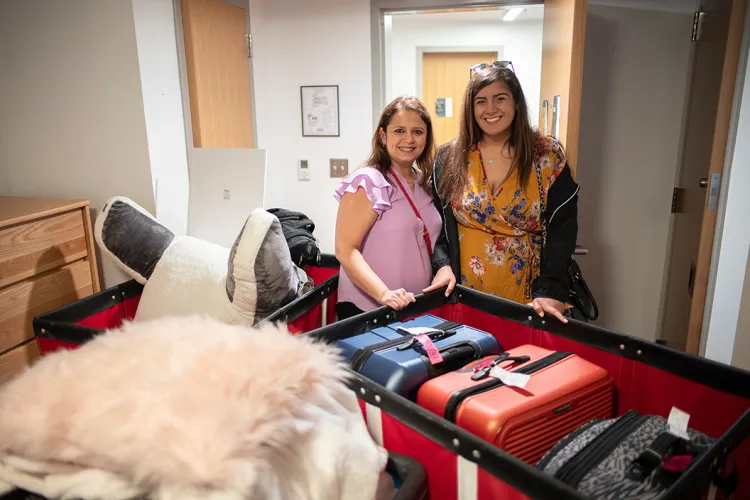 Student pushes cart with belongings into dorm