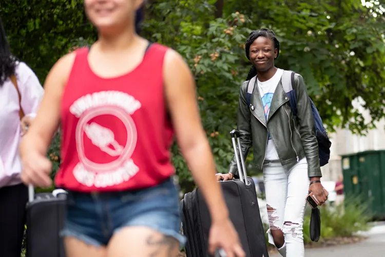 Student pushes cart with belongings into dorm