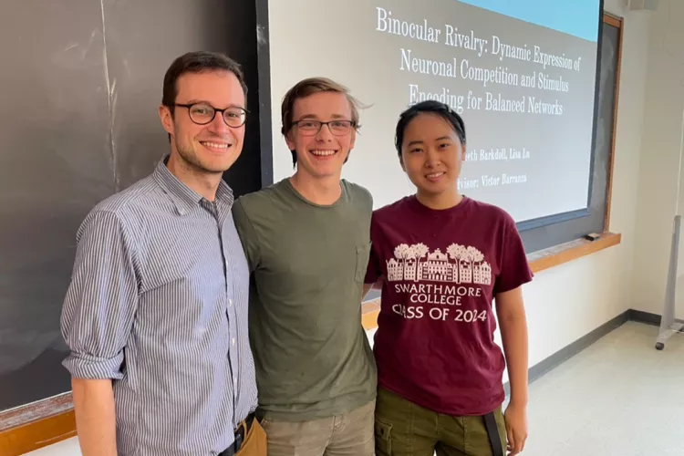 Three people stand in front of blackboard