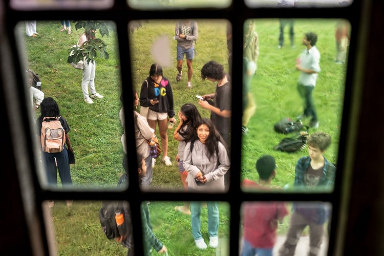 Students on lawn framed by glass window pane