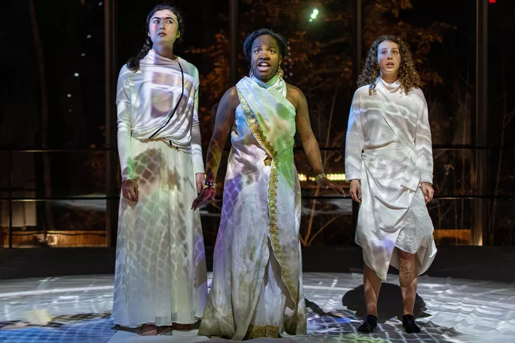 Three students stand on stage during Cassandra dress rehearsal