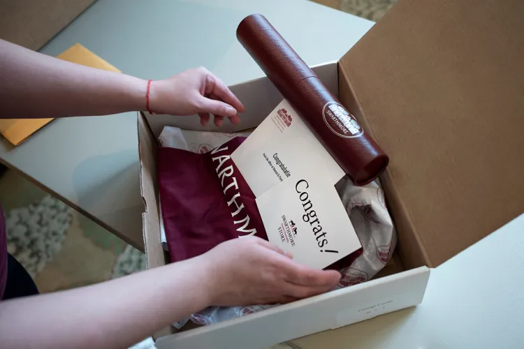 Closeup of hands putting garnet diploma into box