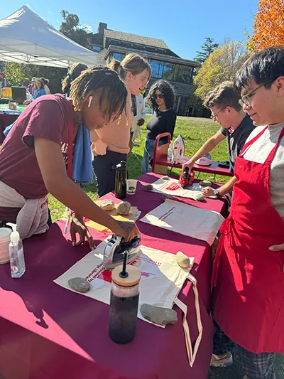 Community members press design onto canvas tote bag