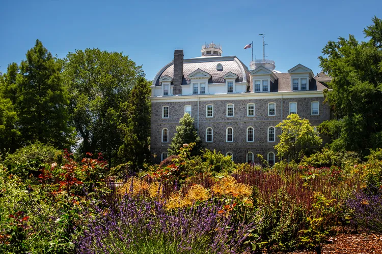 Flowers bloom in Dean Bond Rose Garden with Parrish Hall in background