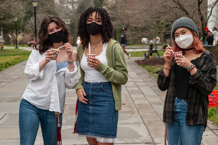 Students wearing masks eat water ice from Rita's outdoors.