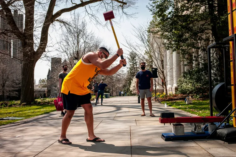 Student in yellow tank top plays carnival game with hammer