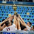 Swimmers hold their championship trophy above theirs heads in the pool