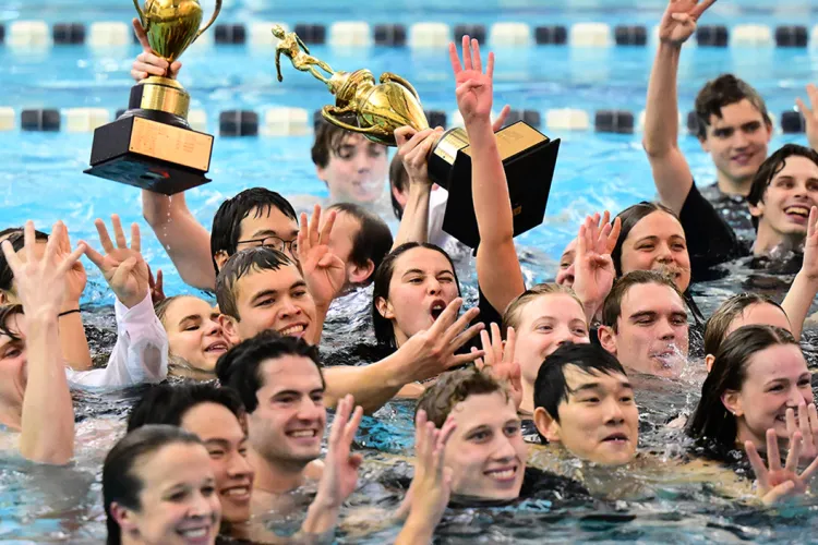 swimmers celebrate with trophy in pool