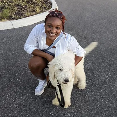 Gabriella kneeling beside a fluffy, white dog 