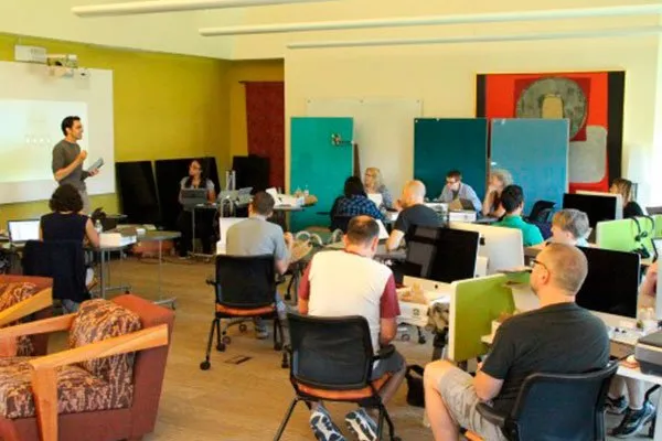 Faculty sitting at computer desks listening to Professor Hauze present about teaching with iPad Pros.