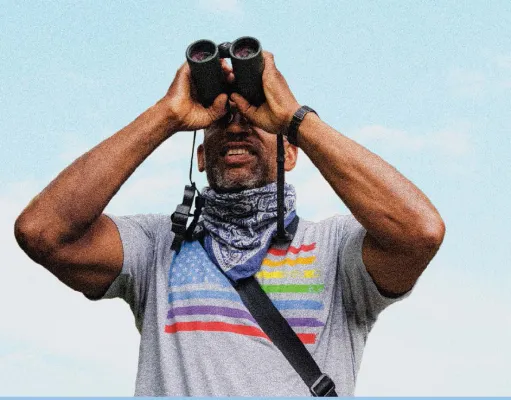 Photo of Christian Cooper looking through binoculars 