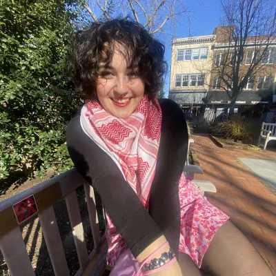 Hannah seated on a bench outdoors on a sunny day