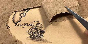 tweezers pull back some old paper backing to reveal a hand drawing of a ship on a map near the Cape May, New Jersey peninsula