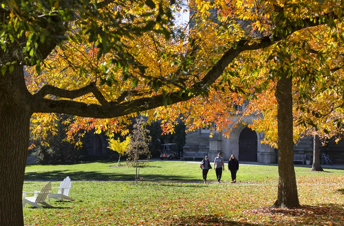 Students walking across Parrish Beach with fall foliage