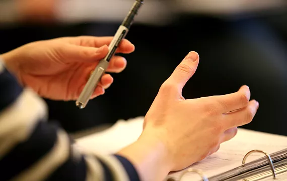 A student's hands over an open book during class.