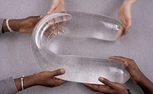 Closeup picture of hands holding a u-shaped sculpture on a table.